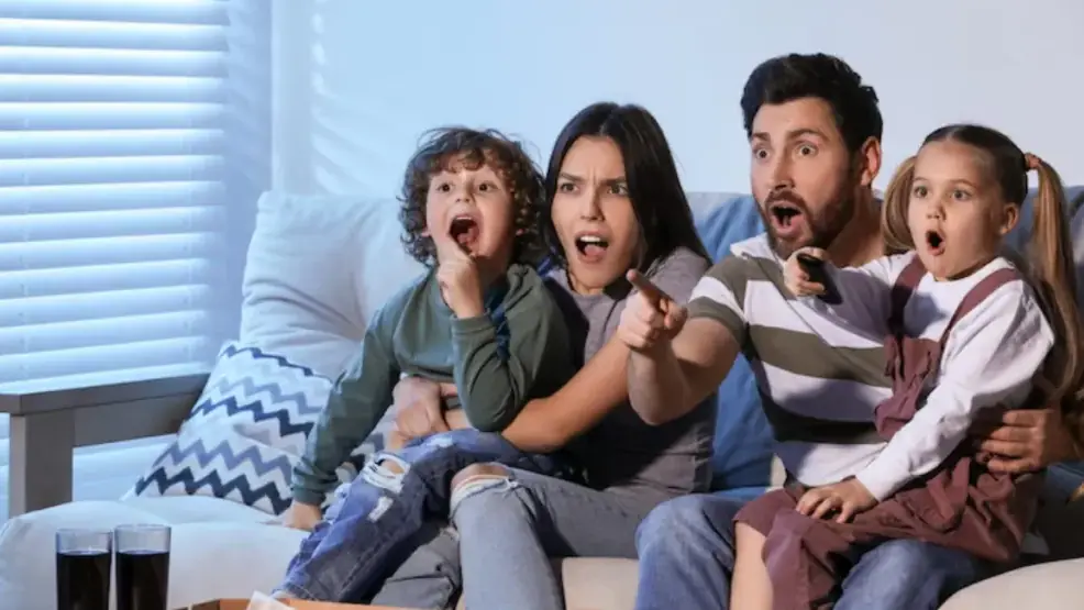 Família e amigos reunidos diante da TV na sala