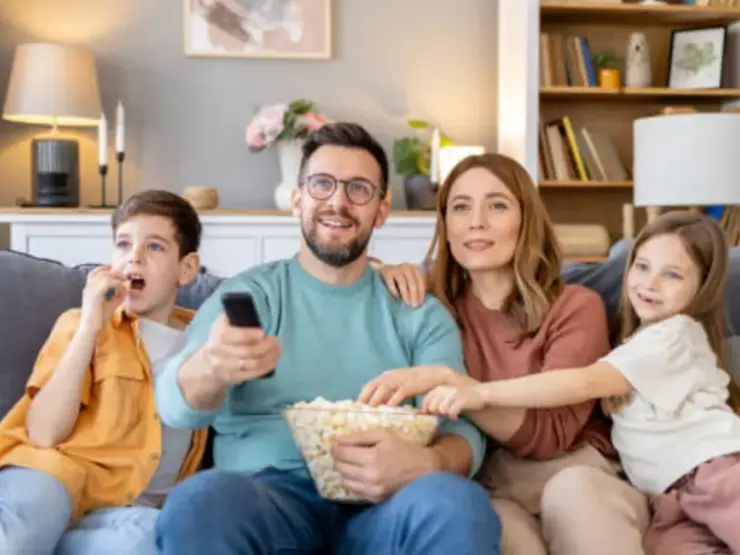 Família e amigos reunidos diante da TV na sala