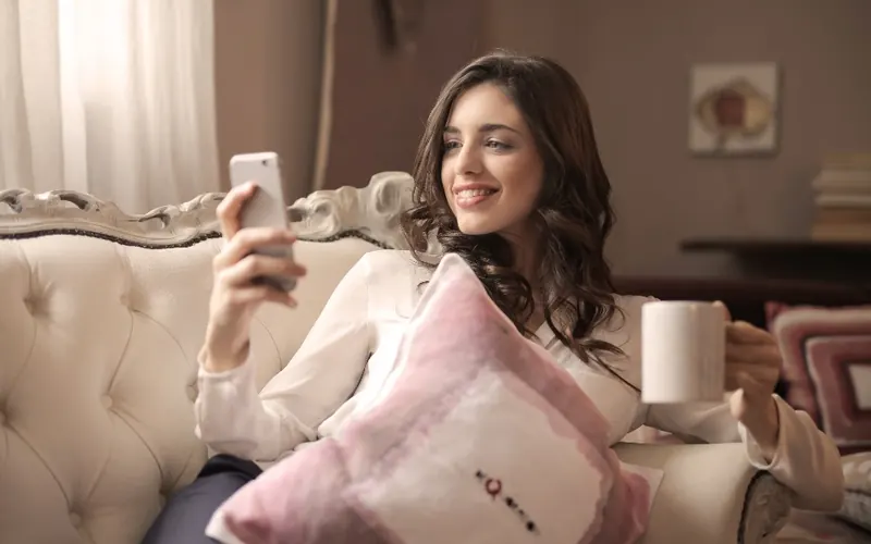 Mulher com celular e café na sala