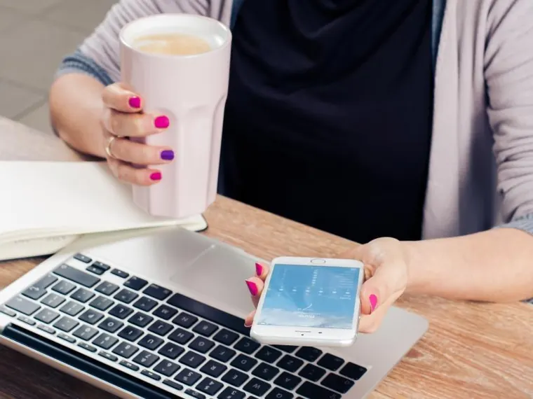 Mulher com celular e notebook no escritório