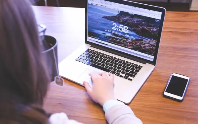 Mulher com celular e notebook no escritório